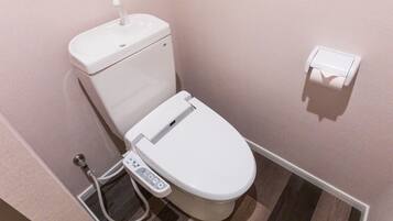 A modern bathroom with a toilet, bidet, and a control panel.