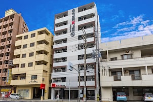 Um hotel de vários andares com uma placa chamativa, várias varandas e um céu limpo.