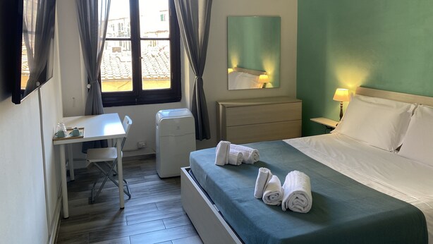 Une chambre d’hôtel équipée d’un lit, d’un bureau, d’une chaise, d’un radiateur et d’une fenêtre avec des rideaux.