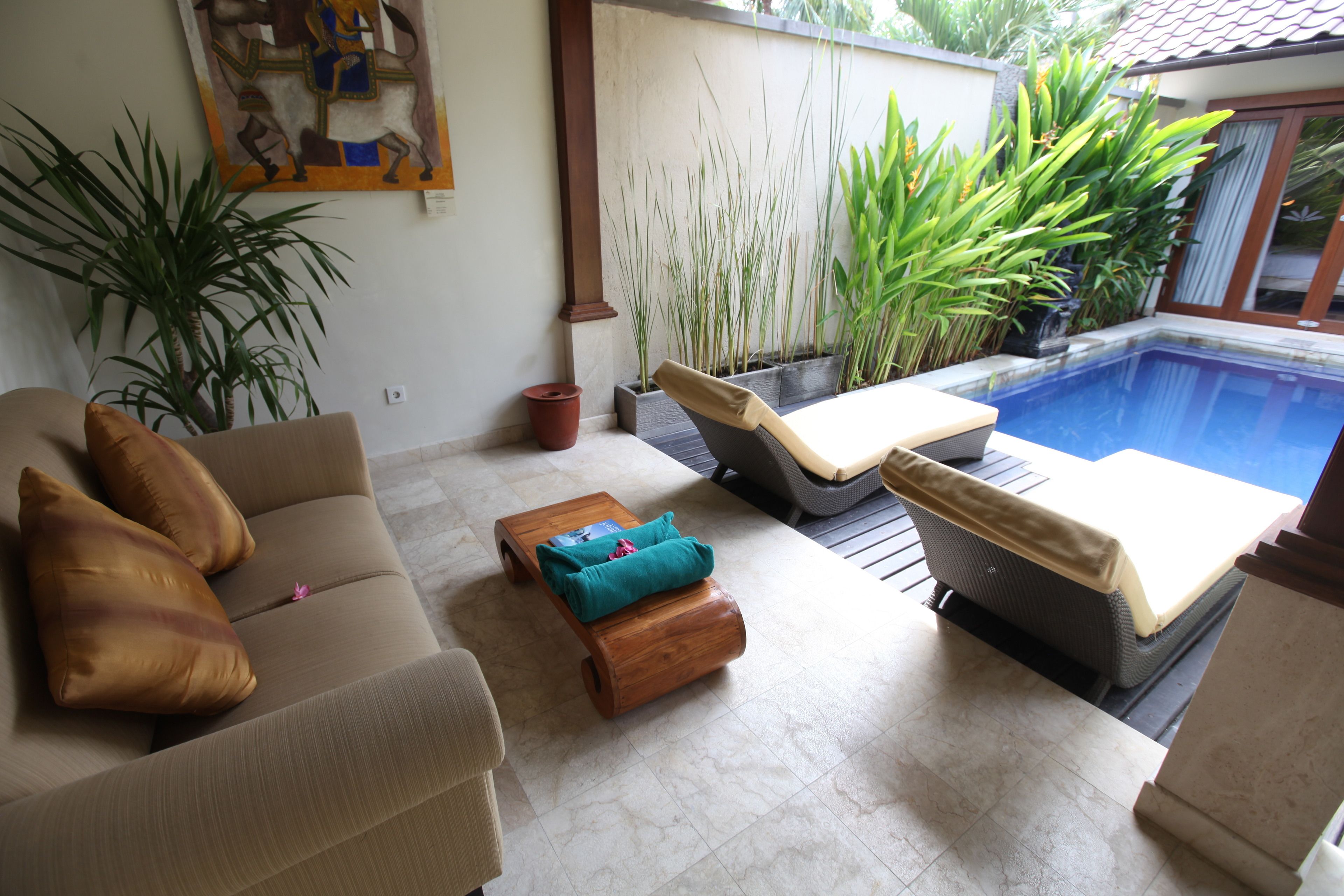 Ein Wohnbereich mit einer Couch, zwei Sessel, einem kleinen Tisch und einem Pool.