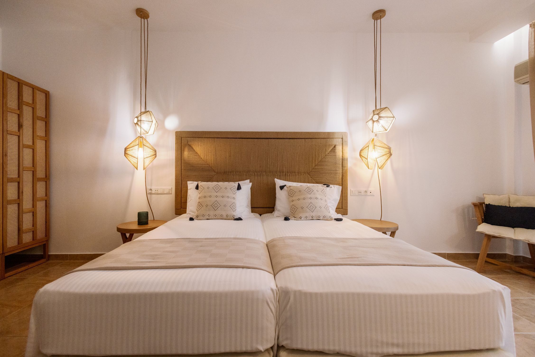A double bed with a wooden headboard, two bedside tables with lamps, and a wooden chair.