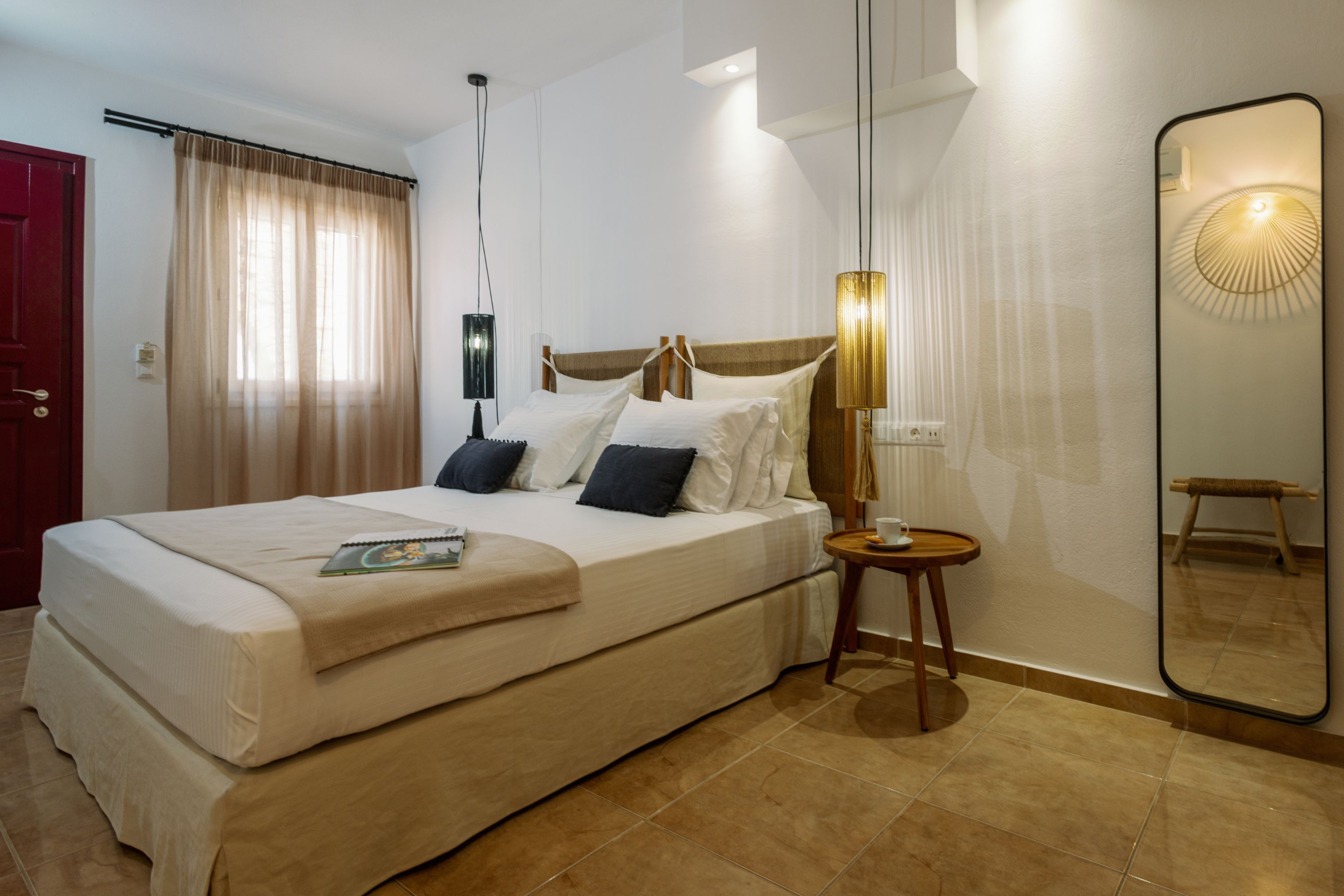 Ein Hotelzimmer mit einem großen Bett, einem Nachttisch, einem Spiegel und einer Tür.