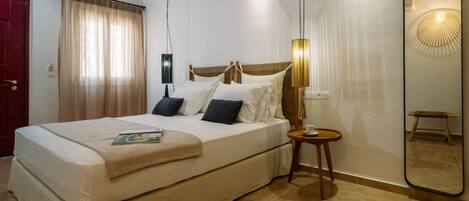 Ein Hotelzimmer mit einem großen Bett, einem Nachttisch, einem Spiegel und einer Tür.