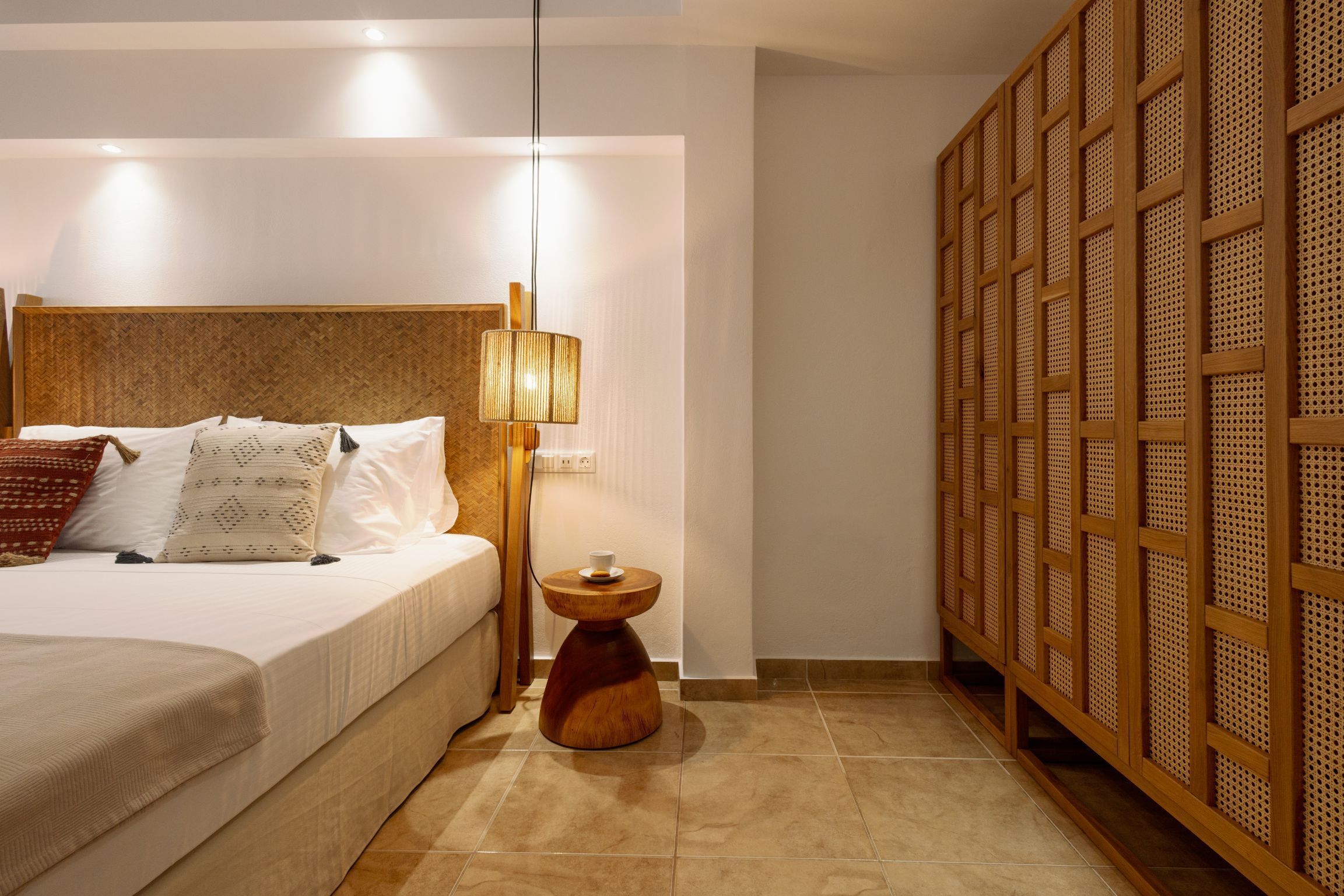 A neatly arranged hotel room with a bed, bedside lamp, and a wooden panel wall.