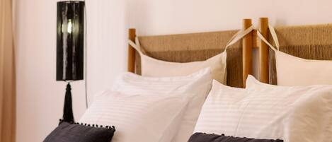 A neatly made bed with white and dark pillows, a wooden headboard, and a black lamp on the nightstand.