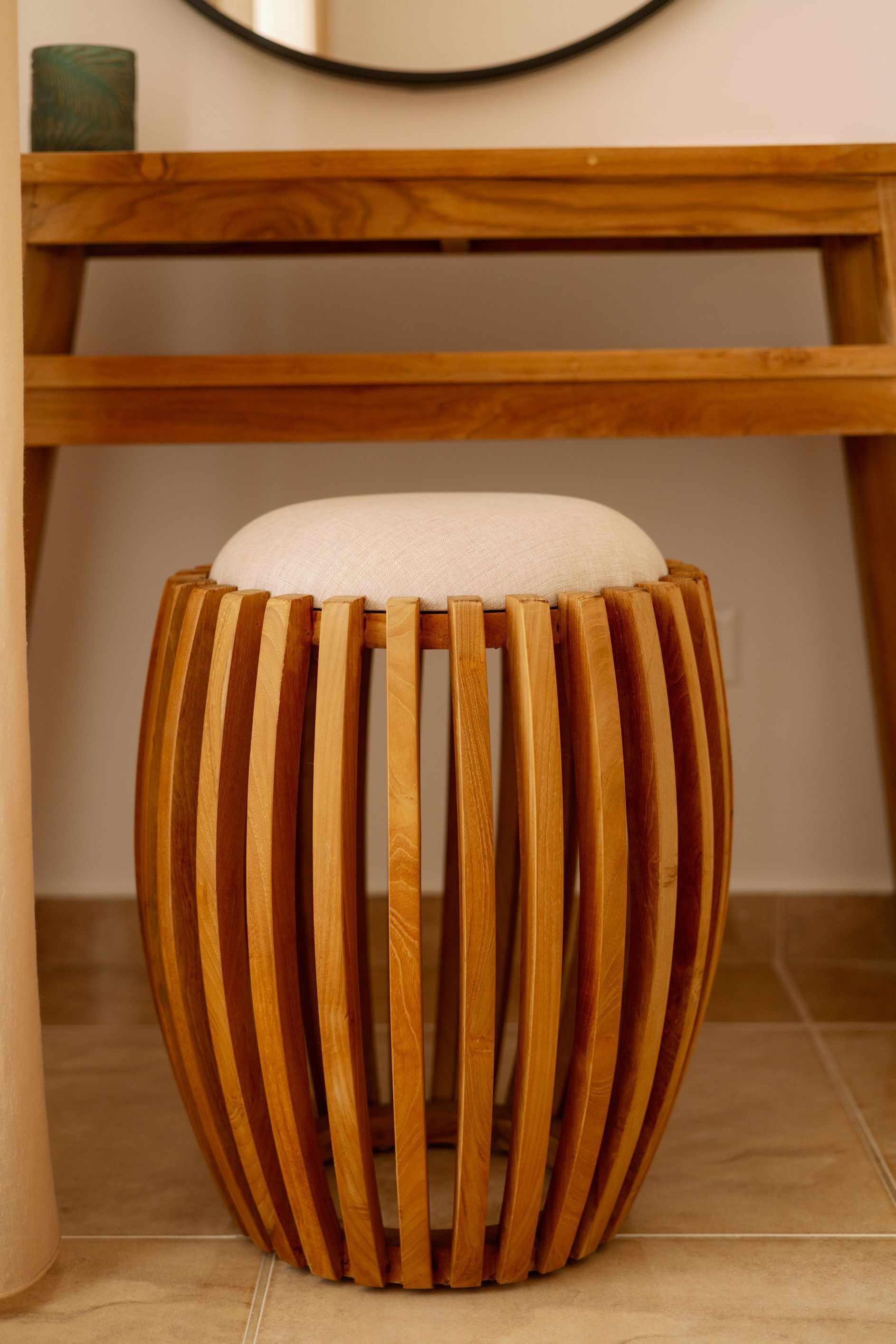 Un taburete de madera con listones verticales y un cojín.