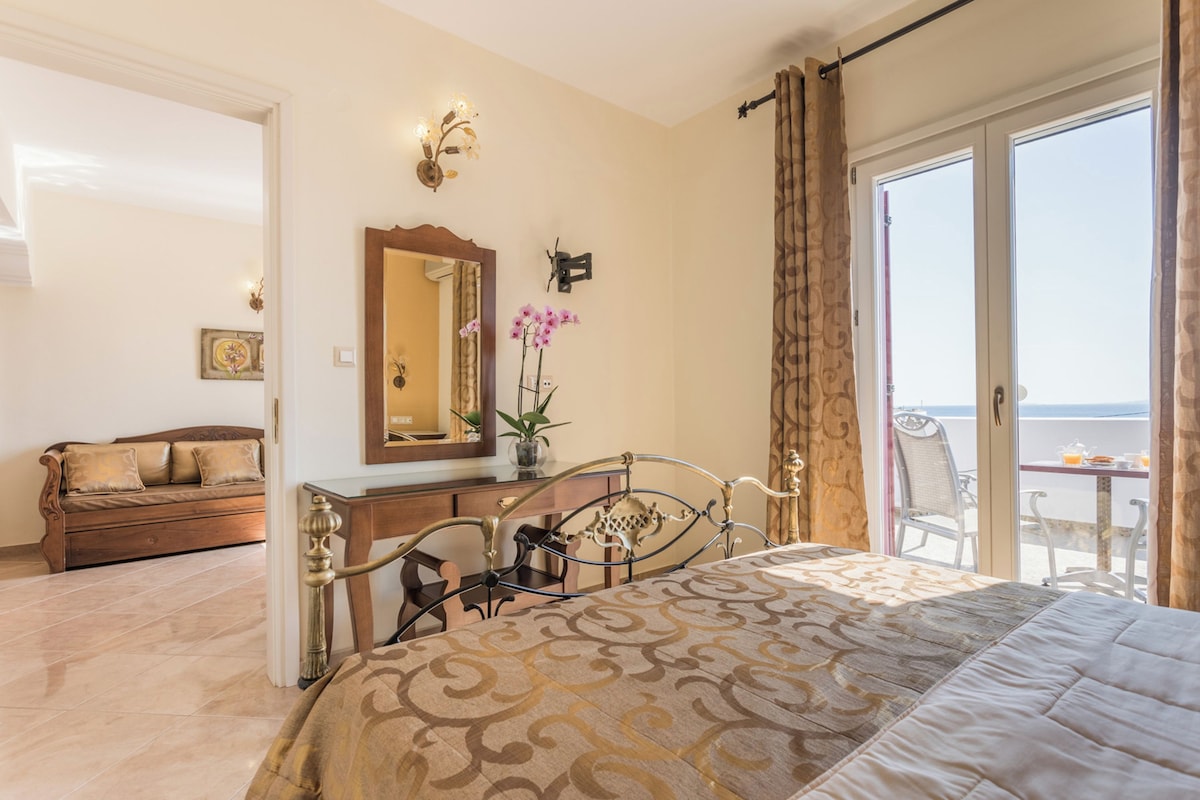 A bedroom with a bed, a dresser, a mirror, and a view of the sea.