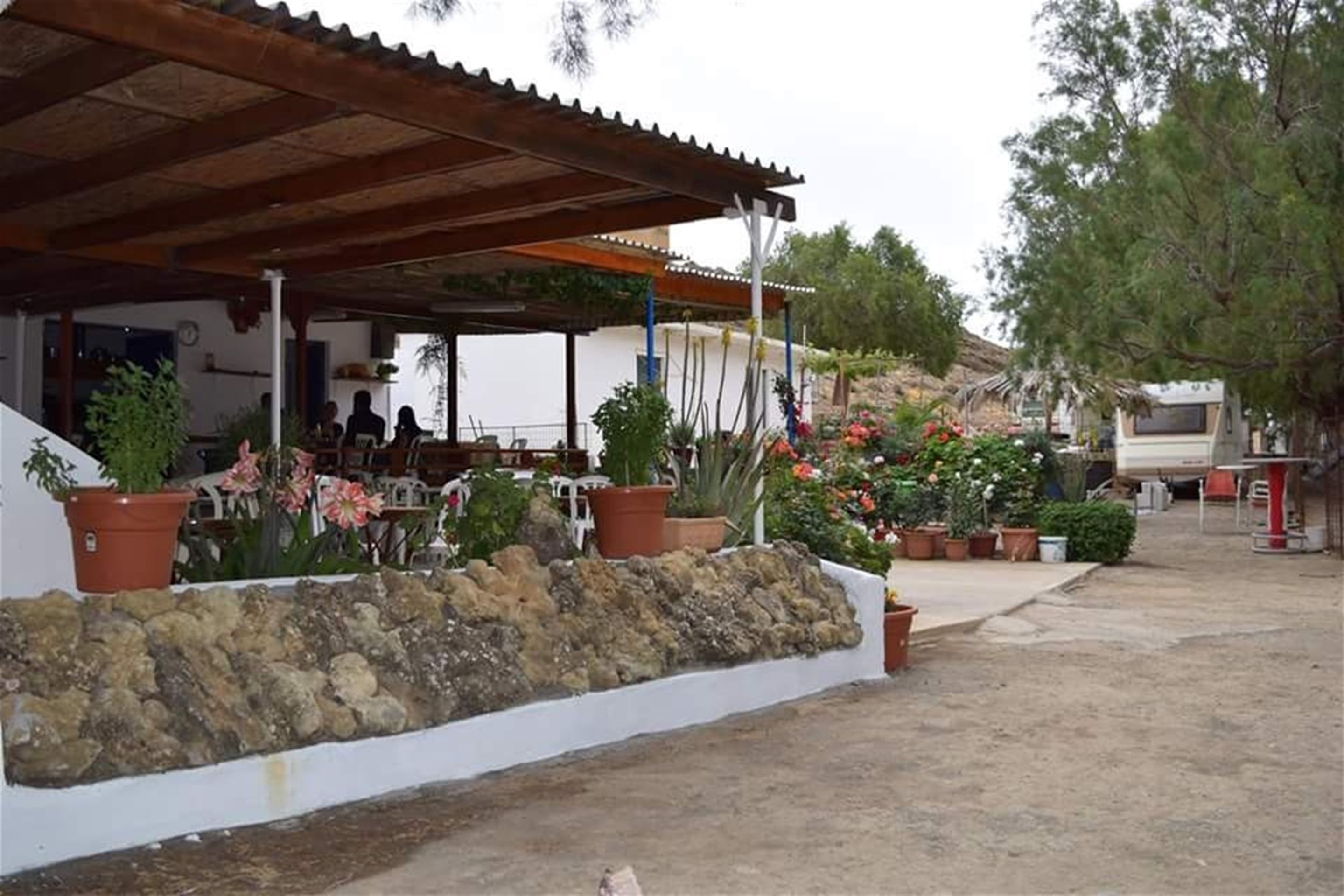 A covered outdoor seating area with stone walls and potted plants.