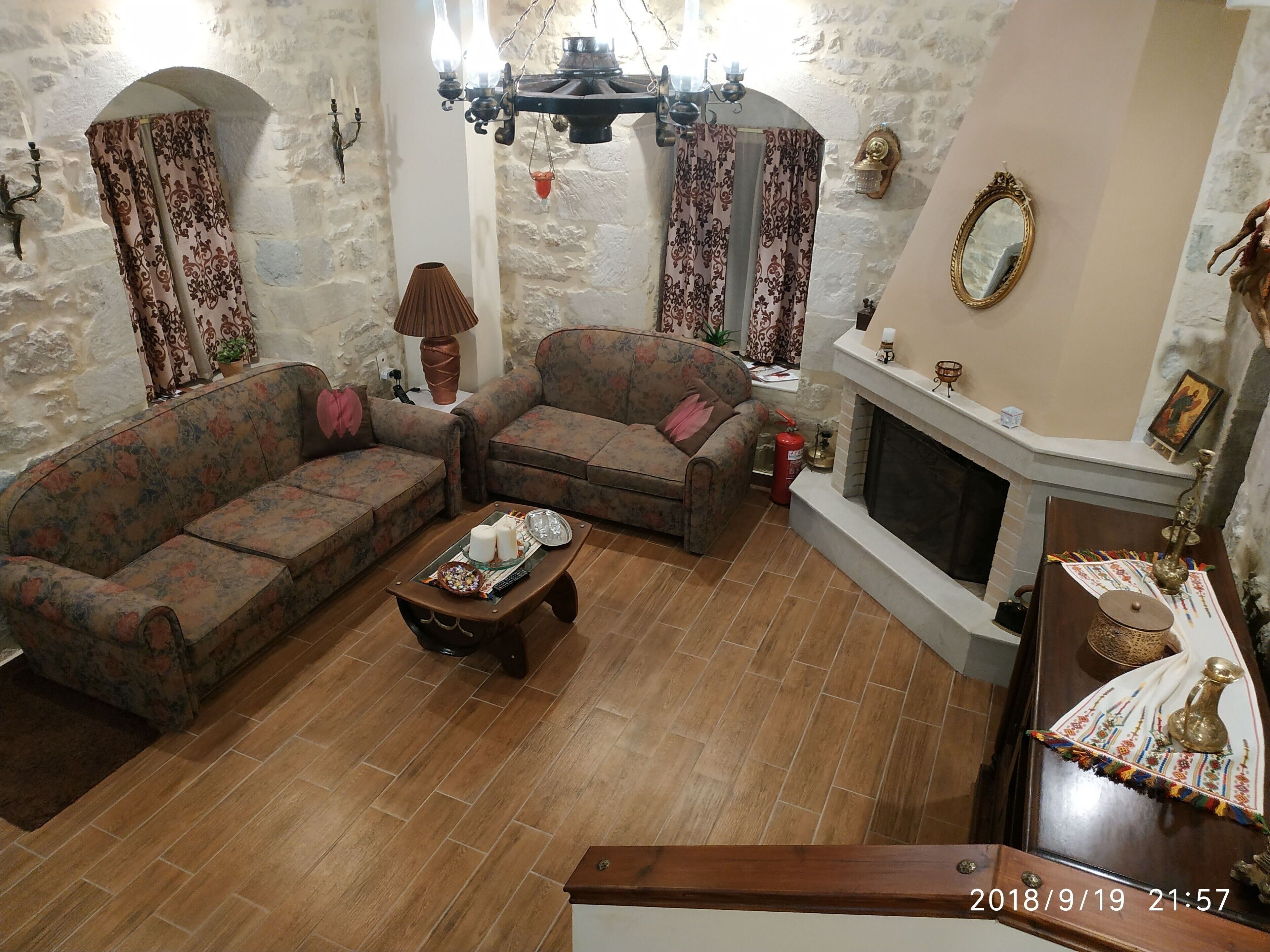 A living room with two sofas, a coffee table, a fireplace, and a stone wall.