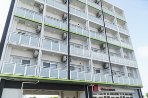 A multi-story building with balconies, air conditioning units, and a sign for 'Mr. KINJO'.