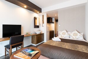 A modern hotel room with a bed, a desk, a TV, and a kitchenette. - Mr.KINJO in OKINAWA KITAINTER (Okinawa)