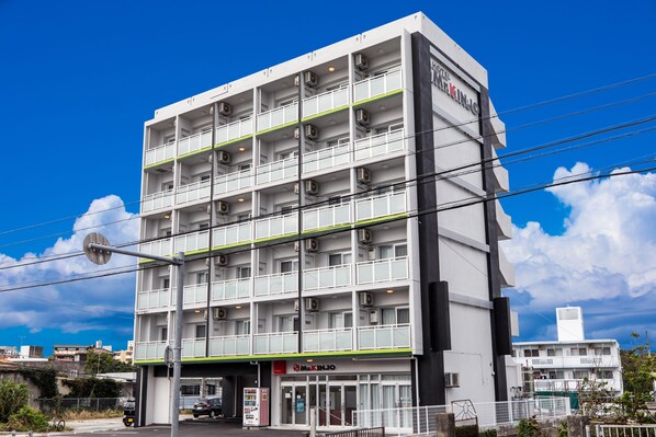 A multi-story hotel with a modern design, featuring a prominent entrance and a signboard.
