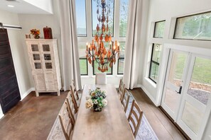 A dining area with a wooden table, chairs, a chandelier, and a cabinet with flowers. - 4BR Canyon Lake Retreat with New Private Pool & Outdoor Living (Canyon Lake)
