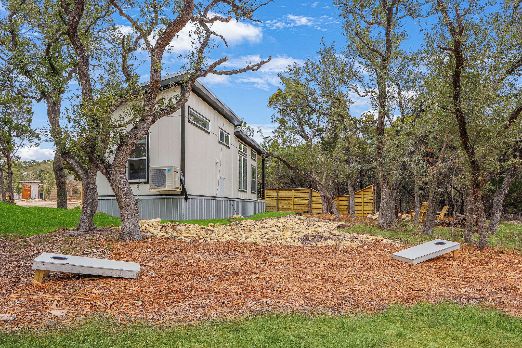 A house with a yard, two trampolines, and trees.