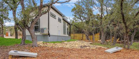 A house with a yard, two trampolines, and trees.