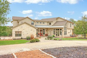 A two-story building with a stone facade, a red door, and a covered entryway. - 4BR Canyon Lake Retreat with New Private Pool & Outdoor Living (Canyon Lake)