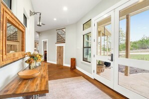 A spacious room with a wooden dining table, a large window, and a door leading outside.