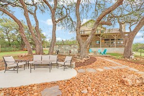 Un patio con mobiliario exterior, un sendero de piedra y un árbol grande.