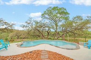 A swimming pool with surrounding patio furniture and a natural landscape. - 4BR Canyon Lake Retreat with New Private Pool & Outdoor Living (Canyon Lake)