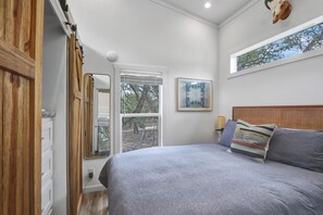 Un dormitorio con cama, ventana y puerta de madera.