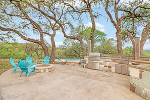 Une terrasse extérieure équipée d’un barbecue, de sièges et d’une piscine.