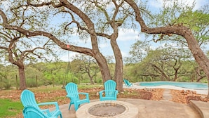 A patio with Adirondack chairs, a fire pit, and a swimming pool. - 4BR Canyon Lake Retreat with New Private Pool & Outdoor Living (Canyon Lake)