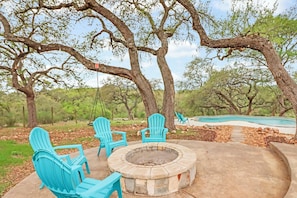 A patio with Adirondack chairs, a fire pit, and a swimming pool. - 4BR Canyon Lake Retreat with New Private Pool & Outdoor Living (Canyon Lake)