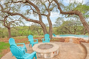 Une terrasse avec des fauteuils Adirondack, un foyer et une piscine.