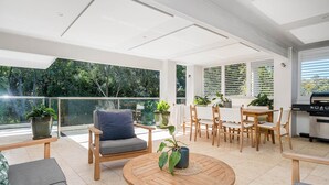 Un balcon spacieux avec un coin repas, un barbecue et des plantes en pot.