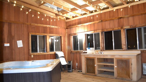 A wooden interior with a hot tub, bar area, and large windows. - Near town & Golf, Sleeps 15, 3,300sqft, 1.9 Acres, 6BR w/4Kings, Game Room, HVAC (Williams)