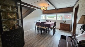 A dining area with a table and chairs, a chandelier, and a view through large windows. - Near town & Golf, Sleeps 15, 3,300sqft, 1.9 Acres, 6BR w/4Kings, Game Room, HVAC (Williams)
