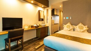 A hotel room with a bed, a desk with a chair, a TV, a sink, and a mirror. - Mr.KINJO in MOTOBU OCEAN TERRACE (Motobu)