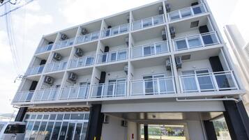 A multi-story building with balconies, air conditioning units, and a covered entrance area.