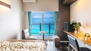 A hotel room with a bed, a desk, a TV, a small table, and a view of the sea. - Mr.KINJO in MOTOBU OCEAN TERRACE (Motobu)