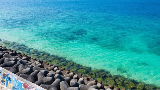A clear view of a coastal area with a rocky breakwater and calm sea. - Mr.KINJO in MOTOBU OCEAN TERRACE (Motobu)