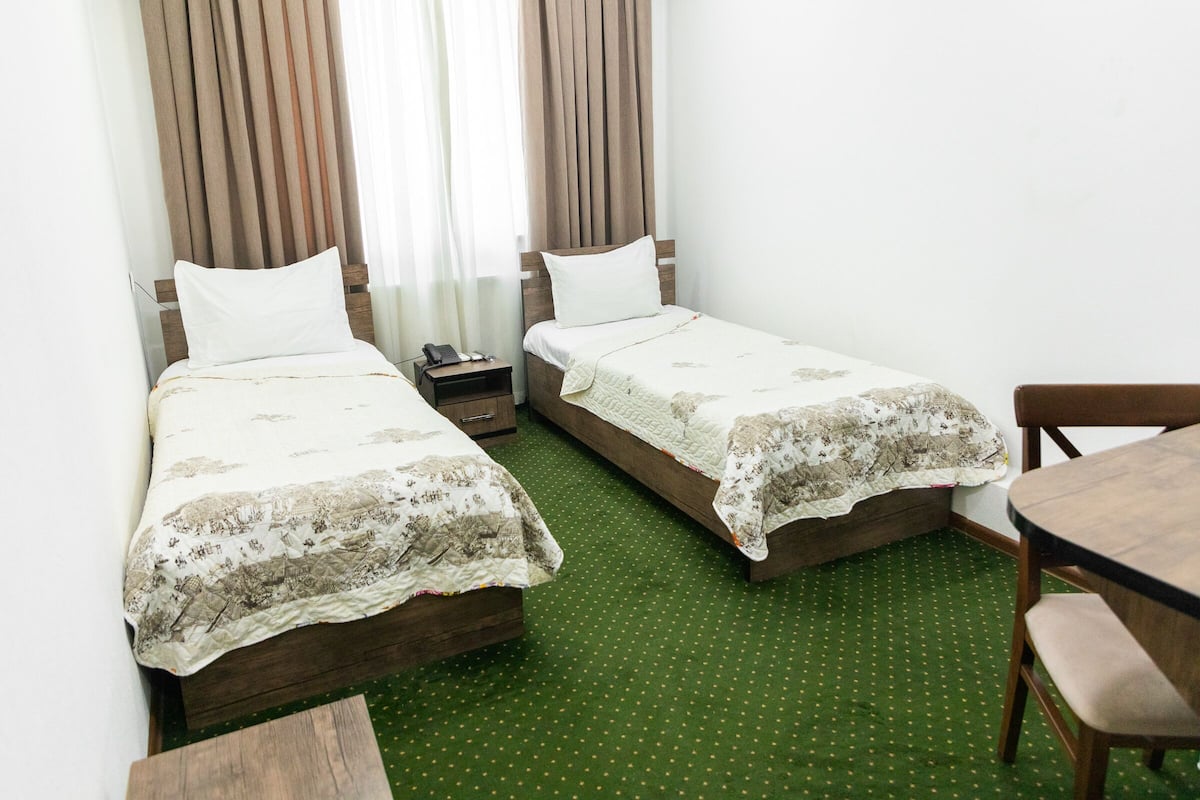 Une chambre d’hôtel avec deux lits simples, une petite table et une chaise.