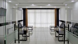 A conference room with a glass partition, black chairs, a white table, and a large window with curtains. - Magistral (Urtaaul)