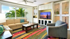 A living room with a sofa, armchair, coffee table, TV, and cabinets. - Luxury 3-Bedroom Waterfront Home with Pool AND Dock! (Key West)