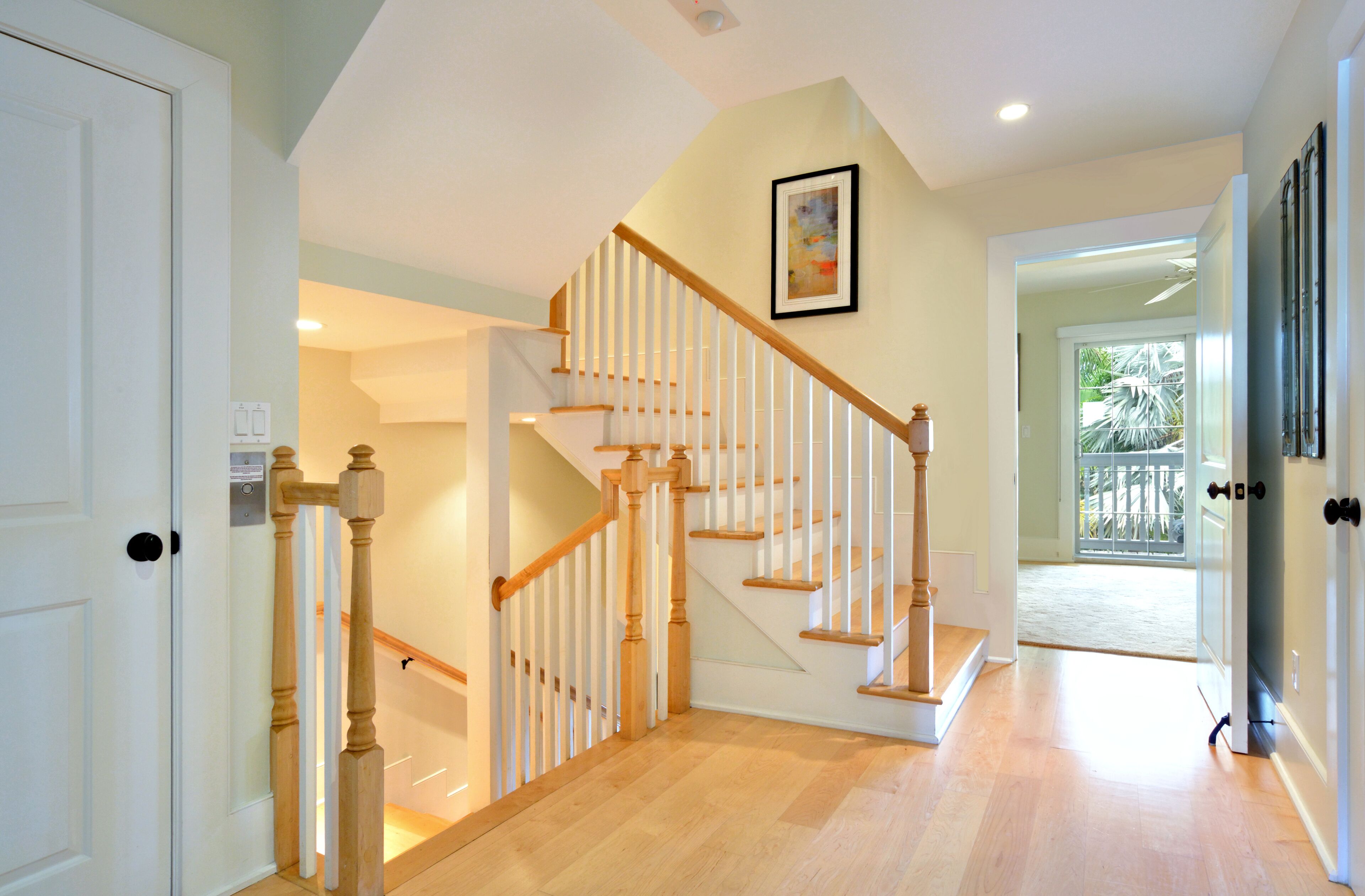 Un escalier avec des rampes et une main courante en bois, menant à l’étage supérieur.