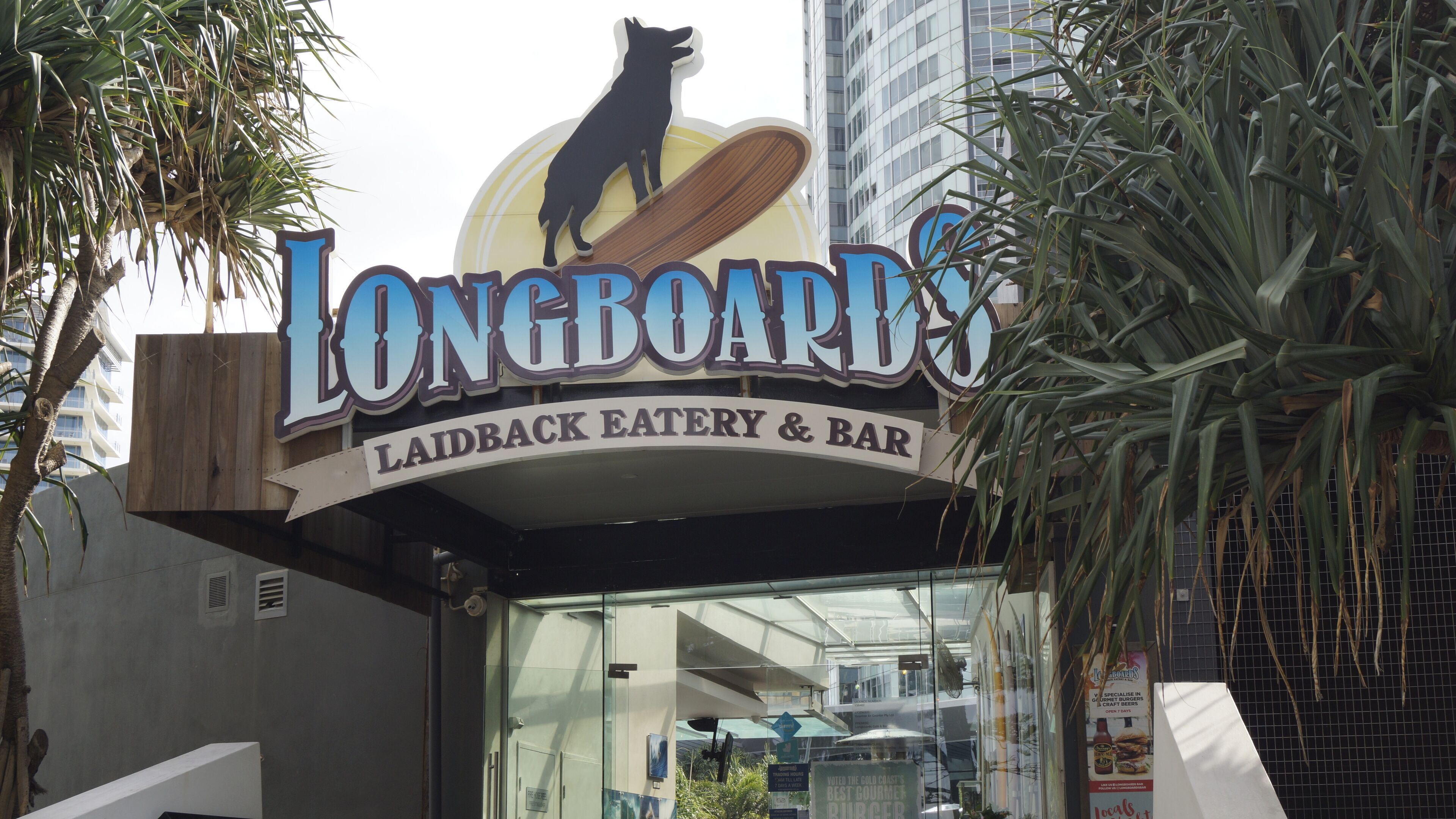 A sign for Longboard's Laidback Eatery & Bar with a silhouette of a dog on a surfboard.