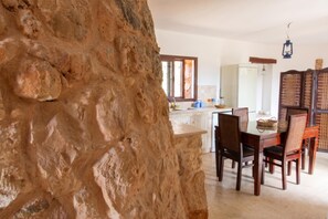Un comedor con pared de piedra, mesa de madera y sillas.