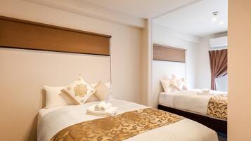 Habitación de hotel con dos camas, cada una con cabecero, un espejo grande y una ventana con cortinas.