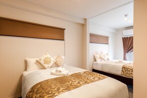 A hotel room with two beds, each with a headboard, a large mirror, and a window with curtains. - Mr.KINJO in PREMIUM TERRACE CHATAN (Chatan)