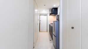 A narrow hallway leading to a kitchen with white walls, a refrigerator, and a microwave. - Mr.KINJO PREMIUMHOME in CHATAN 2 (Chatan)