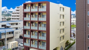 A multi-story building with a central courtyard, balconies, and a parking area. - Mr.KINJO PREMIUMHOME in CHATAN 2 (Chatan)