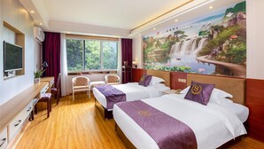 Une chambre d’hôtel avec deux lits, un bureau, des chaises, une télévision et une grande fresque représentant une cascade.