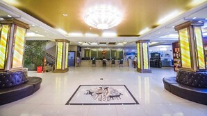 Un hall d’hôtel avec un lustre, un comptoir d’accueil et un espace salon.