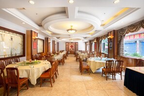 Ein Restaurant mit mehreren runden Tischen und Stühlen, einem gefliesten Boden und einer dekorativen Decke.