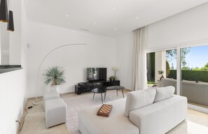 A modern living room with a flat-screen TV, a gaming table, and a sofa. - Villa near Beach with Pool & Panoramic Views (Marbella)