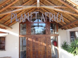 The entrance of a building with a wooden facade and a sign that reads "PLANETAFRICA". - Planet Africa (Cape Town)